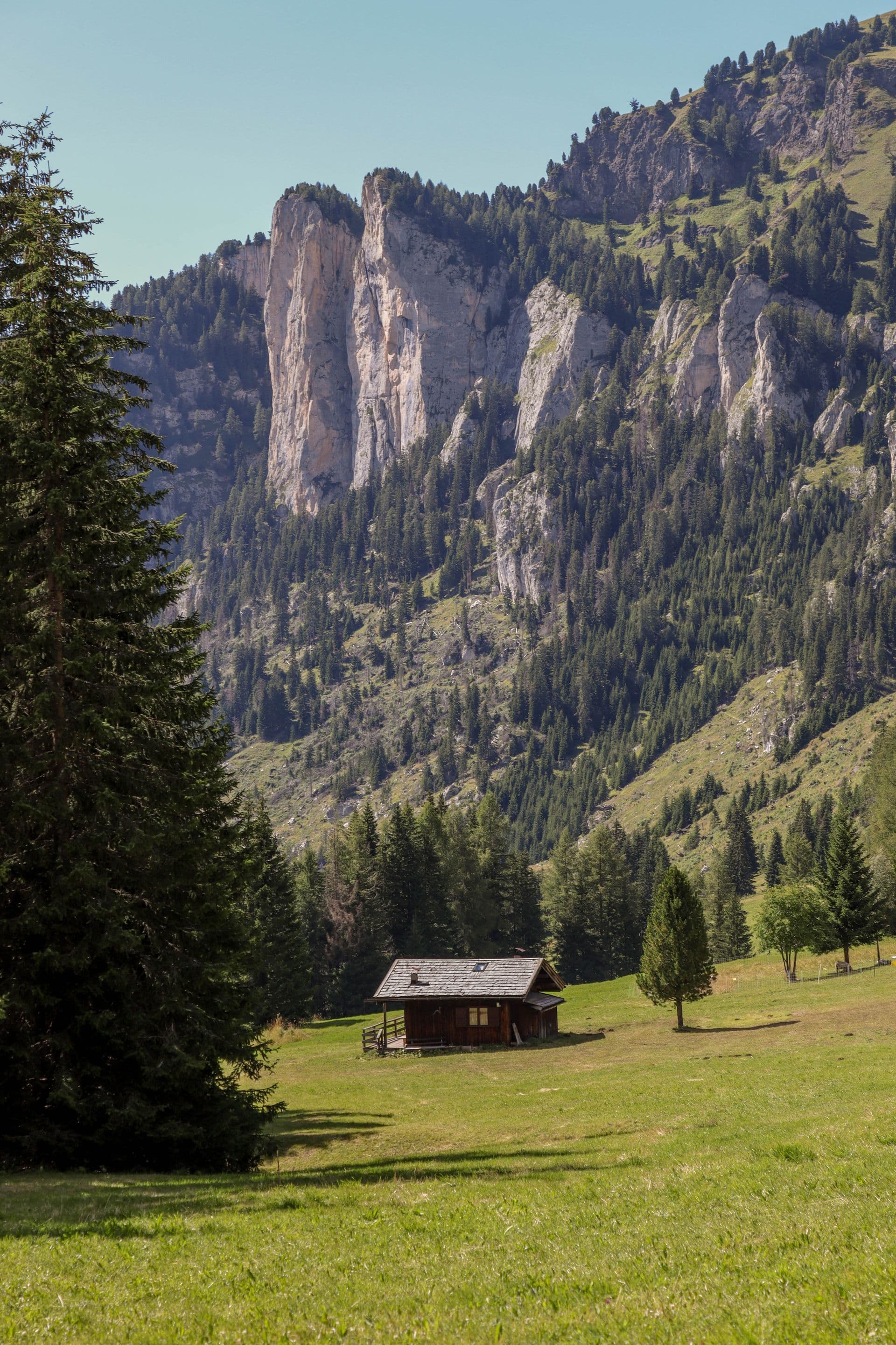 A cabin in a green mountain meadow below dramatic cliffs near Kamas, Utah — gateway to the Uinta Mountains.