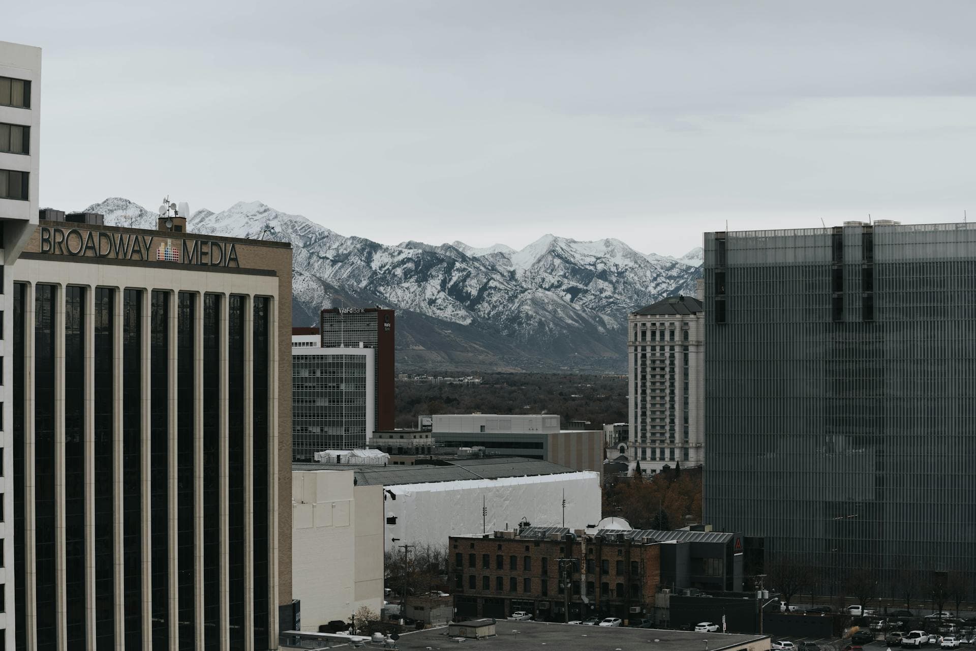 Downtown Salt Lake City buildings with the snow-capped Wasatch Range rising behind.